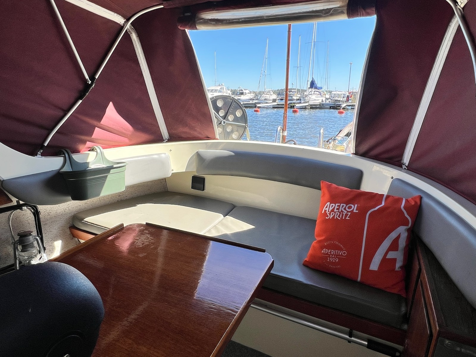 Corinnes sittbrunn med träbord, grå dynor och utsikt över hamnen